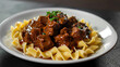 Hearty estonian beef stew with fresh herbs and al dente pasta on a dark table background