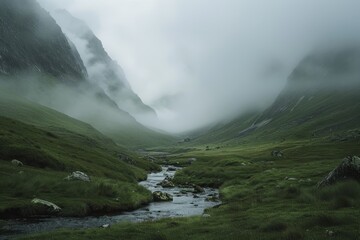 Canvas Print - A stream winds its way through a green valley with misty mountains in the background, A misty mountain range shrouded in fog with a gentle stream running through the valley