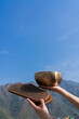 A girl holds Sadhu boards and a Tibetan singing bowl against the background of the blue sky and the Himalayas.