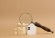 Magnifying glass and a family of wooden figures on the background of a house