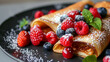 Savor the flavor: delectable crepes with mixed berries and a sprinkle of powdered sugar, topped with fresh mint on a stylish black platter