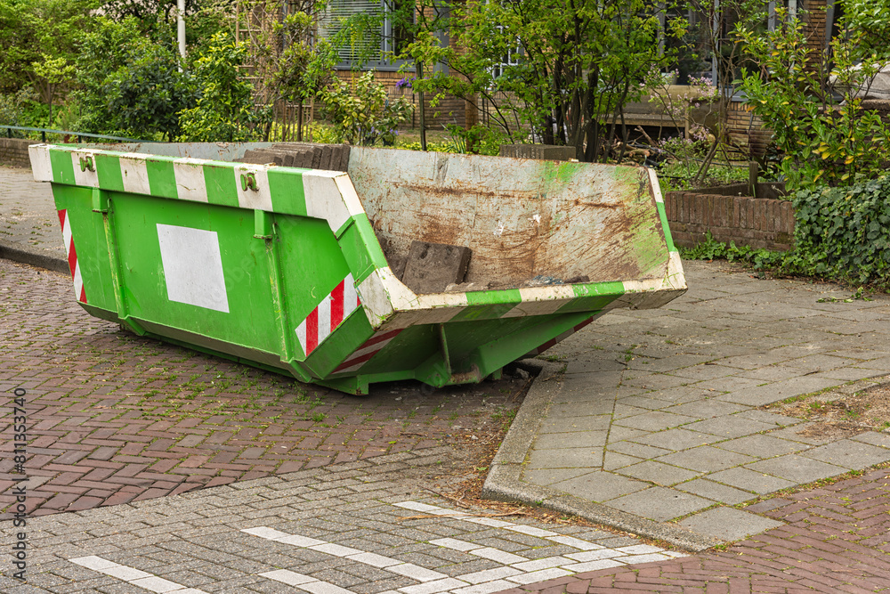 green white open steel industrial waste container stands outside on the street