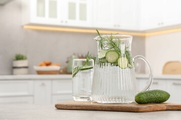 Sticker - Refreshing cucumber water with rosemary and vegetable on table in kitchen. Space for text