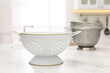 © New Africa - Different clean colanders on white marble table in kitchen