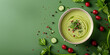 A bowl of seasonal green broccoli cream soup with a green background. The soup is garnished with parsley and celery.