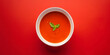A plate of seasonal cream soup from tomato on red background. Empty space for product placement or advertising text around the edges.