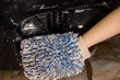 Person using blue glove for closeup car wash with brush and water