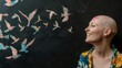 Conceptual photo of young smiling bald woman with cancer, black chalkboard. Banner, mockup, female profile. Flying flock of colorful birds chalk drawn . Rehabilitation, remission, oncology.