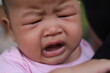 Little Asian newborn baby crying on mother's shoulder