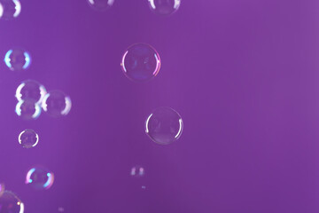 Wall Mural - Beautiful transparent soap bubbles on violet background, space for text