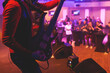 © tsuguliev - Concert view of an electric guitar player with vocalist and rock band performing in a club, male musician guitarist on stage with audience in a crowded concert hall arena, hands on a bass guitar