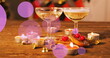 Champagne glasses rest on a table with lit candles and festive decor