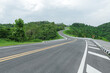 Long curvy forest asphalt road over the hills. Beautiful curved road in the forest. Side view of road with trees