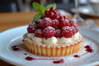 Tartlet with cream and raspberries on plate.