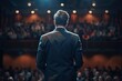 © furyon - back view of a man in a business suit giving a speech on stage in front of an audience leadership concept