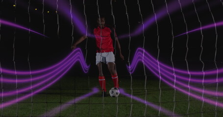 Poster - Image of colorful light trails over african american male soccer player taking a penalty kick