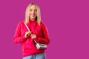 Sticker - Beautiful young woman in stylish hoodie with bag on purple background