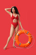 © Pixel-Shot - Beautiful young happy African-American female lifeguard with ring buoy on red background