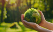 Close up of hands holding the green planet Earth

