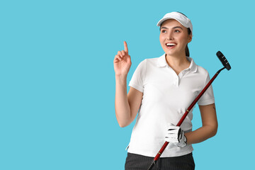 Wall Mural - Beautiful female golfer pointing at something on blue background