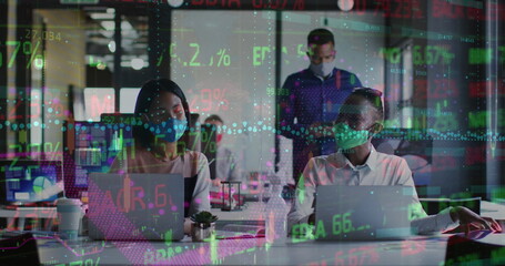 Wall Mural - Image of trading board and graph on diverse coworkers wearing mask talking and working on laptop