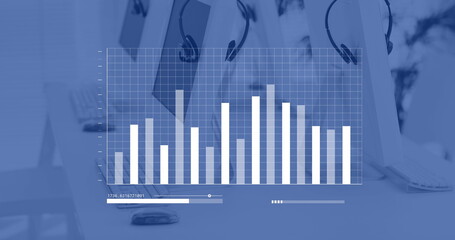 Canvas Print - Blue and white graph processing data over computers and phone headsets on desks in empty office