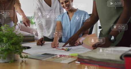 Poster - Anmation of social media icons floating over diverse colleagues discussing over a plan at office