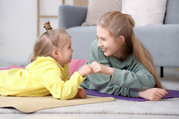 Poster - Sporty little girl with her mother bumping fists at home