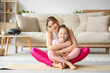 © Pixel-Shot - Young woman with her little daughter hugging on yoga mat at home