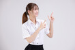 Pretty Asian woman in university student uniform over isolated white background pointing finger to the side.