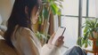 自宅でスマートフォンを使用している若い日本人女性、白い空白の空の画面
