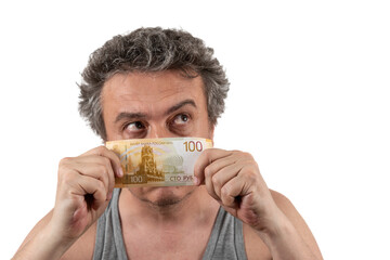 Wall Mural - A gray-haired, shaggy, unshaven middle-aged man in a sleeveless T-shirt holds a 100 Russian ruble bill