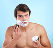 Beauty, man and shaving cream brush in studio for hair removal, hygiene and grooming portrait on blue background. Face, beard and model apply foam for skincare, cleaning and wellness with container