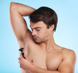 Shaving underarm and man in studio for hair removal, depilation or grooming treatment for hygiene. Self care, health and closeup of male person with razor for body wellness by blue background.