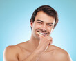 Portrait, brushing teeth and man with dental hygiene, wellness and grooming routine on blue studio background. Face, person or model with oral health, cleaning mouth or remove plaque for fresh breath