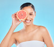 Woman, beauty and grapefruit with skincare glow from spa treatment and natural cosmetics. Model, skin and face of person relax after dermatology detox in a studio with blue background feeling healthy