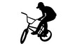 silhouette of boy showing off freestyle trick with bicycle