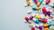© Natalia S. - A variety of colorful pills and capsules scattered on a light blue surface with copy space. Pharmaceutical industry, rising prices of drugs, drug production, shortage of drugs in pharmacies