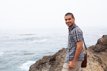 Wall Mural - Man standing on rocky landscape with ocean in the background