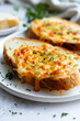 Two slices of bread with cheese and herbs on a plate.