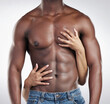 © peopleimages.com - Hands, muscles and body of black man in studio for body building exercise with jeans for fashion. Strong, health and woman holding chest and abs of African male athlete isolated by gray background.