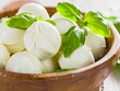 A bowl of mozzarella cheese with basil leaves.