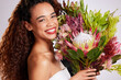 Flowers, woman and happy portrait in studio for skincare, haircare and organic beauty on white background. Brazil female person. bouquet and smile for wellness, summer and curly hair or romantic gift