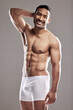 Portrait, man and smile for fitness in health, wellness and underwear, body and sexy in studio background. Male person, confident and strong for pride as model for happiness in grey backdrop