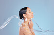 Woman, water splash and shower with cleaning in studio for hygiene, bacteria and dirt by blue background, Girl, person and model for hydration, profile and stop germs for healthy body for skincare