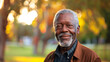 © Lucy - Older senior black man smiling warmly to camera in sunny outdoors setting