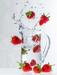 delicious strawberrys beautifully falling into a pitcher of water
