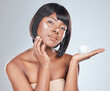 Skincare, palm space and black woman with face cream application in studio for wellness, shine or cosmetics on grey background. Beauty, sunscreen or portrait with anti aging, lotion or collagen promo