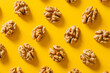 Trendy pattern made with shelled walnuts on bright yellow background