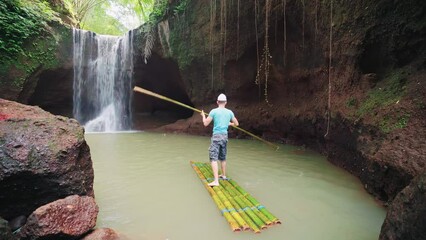 Wall Mural - Active lifestyle travel people explores on a bamboo raft beautiful waterfall in the tropical rainforest jungle 4K